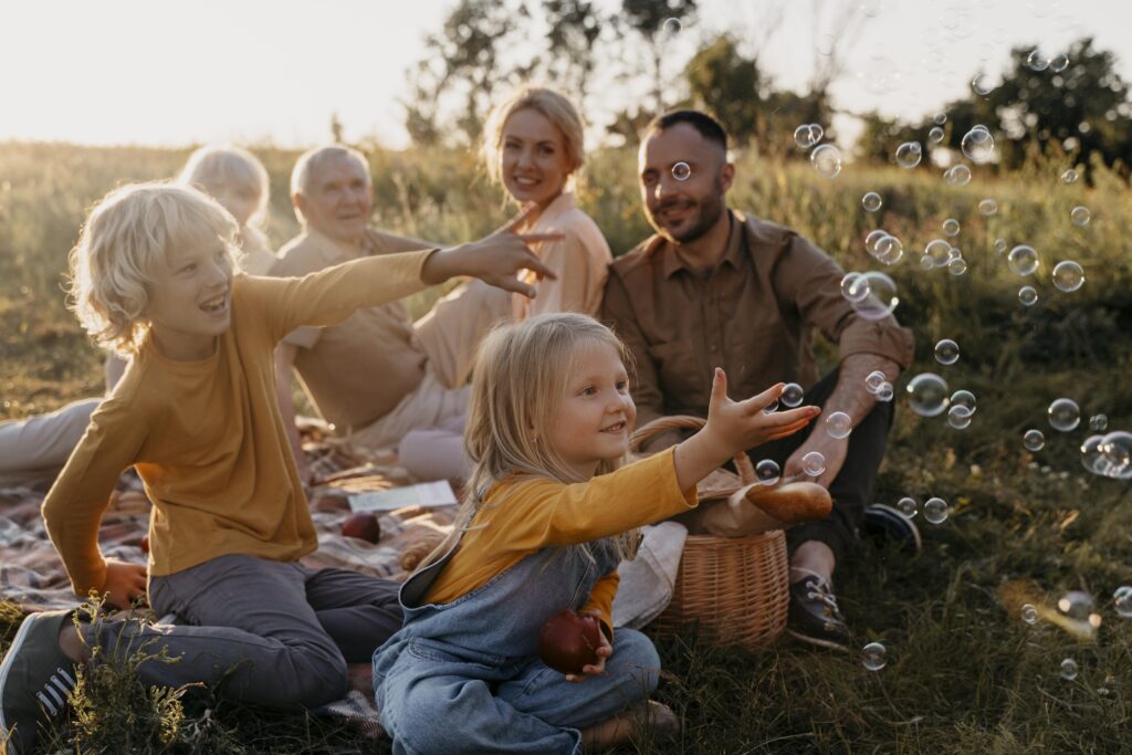 smiling family sitting outside at sun down playing with bubbles